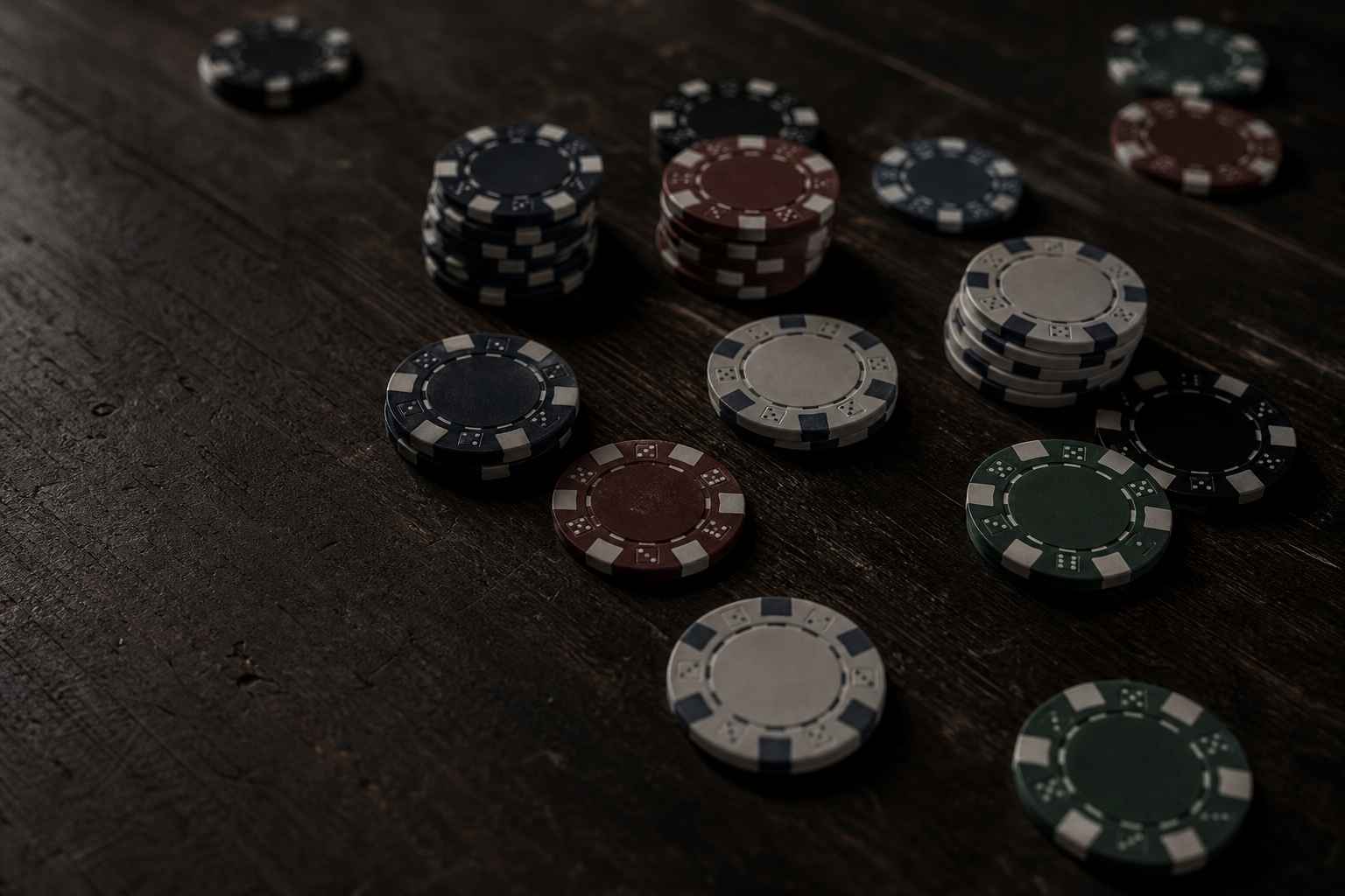 Desaturated casino chips scattered on a dark table